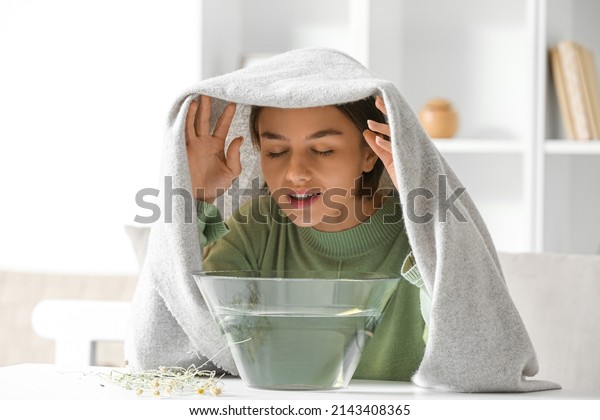 Young woman doing steam inhalation at home to
soothe and open nasal
passages
