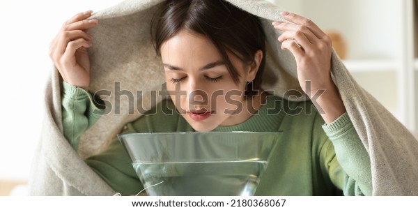 Young woman doing steam inhalation at home to\
soothe and open nasal\
passages