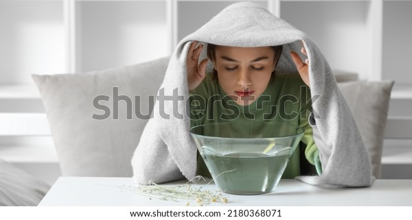 Young woman doing steam inhalation at home to\
soothe and open nasal\
passages