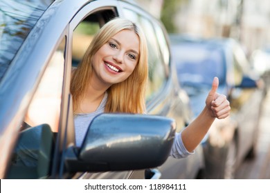 Young woman doing thumps-up in car Foto Stock