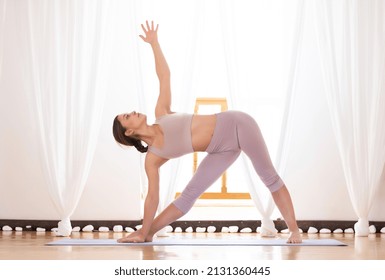 Young woman doing utthita trikonasana pose.