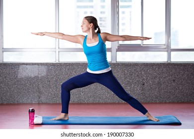 Young Woman Doing Warrior Pose In The Gym