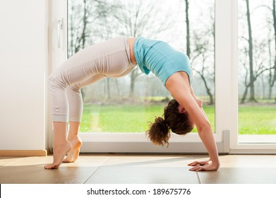 young woman doing yoga bridge pose indoor