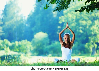 Young Woman Doing Yoga Exercise In Green Park