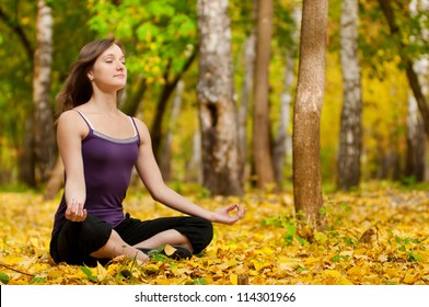 Young Woman Doing Yoga Exercises In The Autumn City Park. Fall