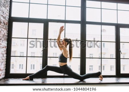 Young woman doing yoga at light window