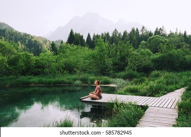 Young woman doing yoga and meditating in lotus position on the background of nature. Concept of Meditation, Relaxation and Healthy Life. Slovenia, Europe.