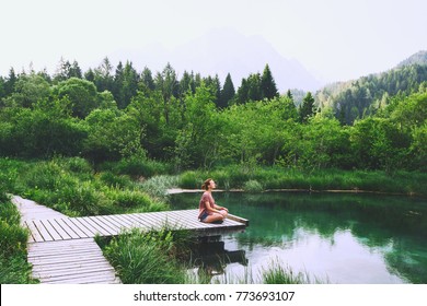 Young woman doing yoga and meditating in lotus position on the background of nature. Concept of Meditation, Relaxation and Healthy Life. Slovenia, Europe.
