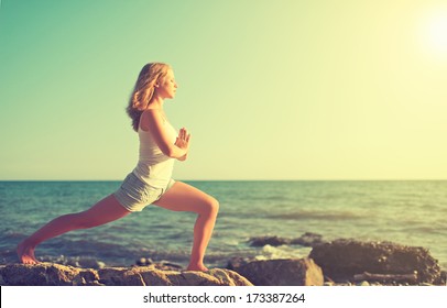 young woman  doing yoga on  coast of  sea on  beach