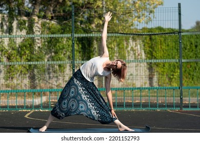 Young Woman Doing Yoga Outside On Court.