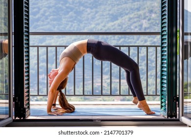 Young woman doing yoga practice in the morning at home. Wheel yoga pose or Urdhva Dhanurasana - Shutterstock ID 2147701379