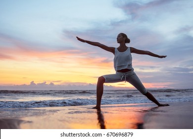 Young woman doing yoga at sunset