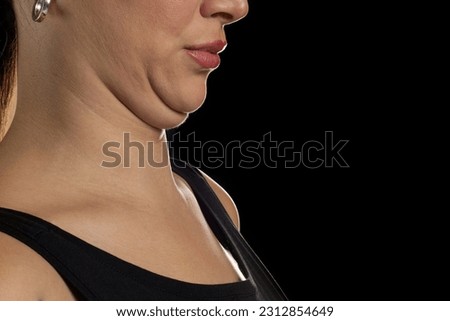 Young woman with double chin on black studio background, closeup. Space for text