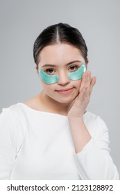 Young Woman With Down Syndrome In Blouse Applying Eye Patch Isolated On Grey