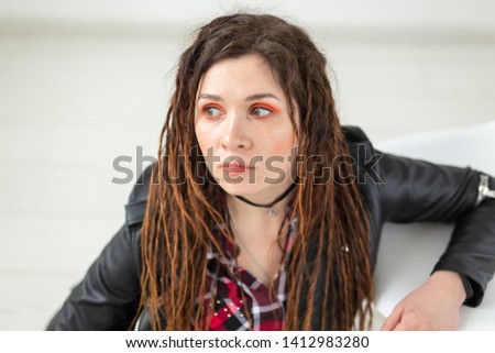 Young woman with dreadlocks and bright make-up looking at something