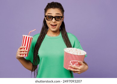 Young woman with dreadlocks wear green t-shirt casual clothes 3d glasses watch movie film hold bucket of popcorn cup of soda pop in cinema isolated on plain pastel purple background studio portrait - Powered by Shutterstock