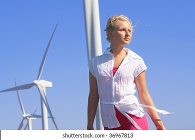 Young Woman Dreams About The Future On A Wind Farm Beneath Eolic Generator