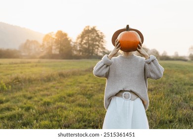 Young woman in dress holding pumpkins in field in autumn. Concept of autumn harvest, fertility, people in nature, life in countryside. Preparing for harvest and autumn holidays. - Powered by Shutterstock