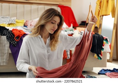 Young Woman With Dress In Messy Room. Fast Fashion Concept