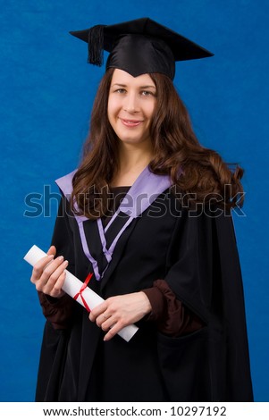 Young woman dressed in black graduation gown holding certificate of degree, standing over blue background.