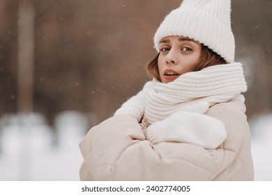 Young woman dressed coat scarf hat and mittens freezing winter weather at snowy winter park - Powered by Shutterstock