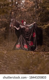 Young woman dressed as mexican symbol of day of the dead posing in forest with horse