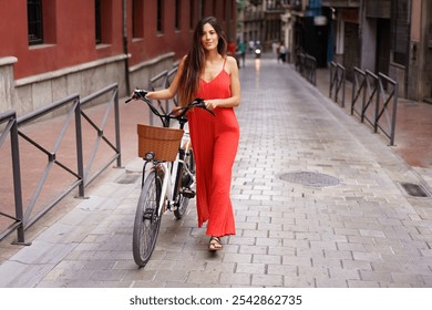 A young woman dressed in a vibrant red outfit stands confidently with her stylish ebike parked nearby on a lively urban street, showcasing her natural elegance, fashionable flair, and unique style - Powered by Shutterstock