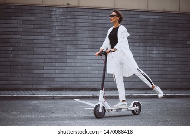 Young Woman Dressed In White Riding Scooter