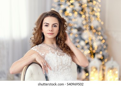 Young Woman In Dressing Gown On Background Of The Christmas Tree Sitting On The Chair, Morning Of The New Year