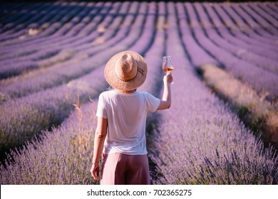 Young Woman Drink Rose Wine In The Sunset Lavender Field, Standing Back To The Camera, Provence, South France