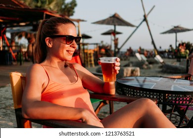 Young Woman Drinking Beer In A Beach Bar Enjoying Sunset