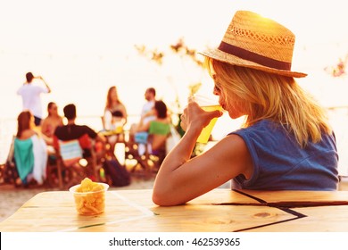 Young Woman Drinking Beer In A Beach Bar