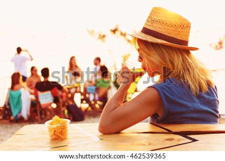 Young woman drinking beer in a beach bar