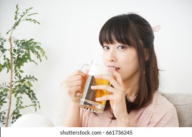 Young Woman Drinking Beer At Home