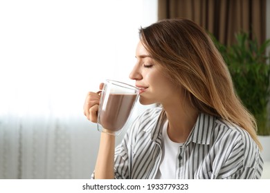 Young Woman Drinking Chocolate Milk In Room