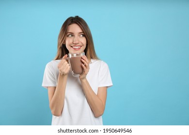 Young Woman Drinking Chocolate Milk On Light Blue Background. Space For Text