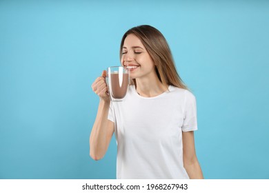 Young Woman Drinking Chocolate Milk On Light Blue Background