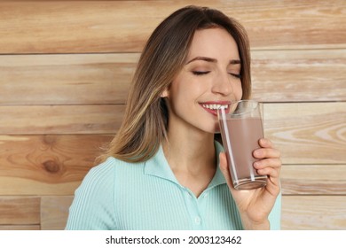 Young Woman Drinking Chocolate Milk On Wooden Background