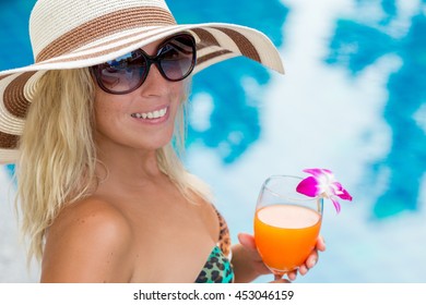 young woman drinking a cocktail in the pool