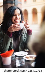 Young Woman Drinking Coffee In A Cafe Outdoors. Shallow Depth Of Field.