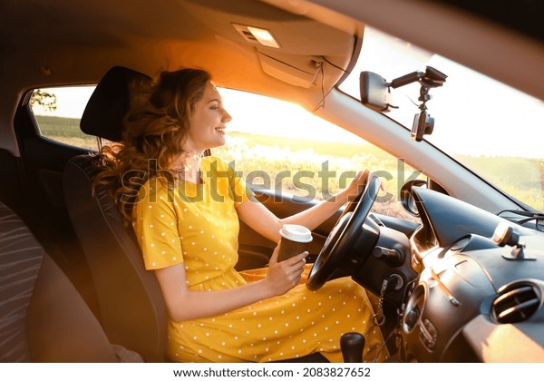 Young woman drinking coffee\
in car