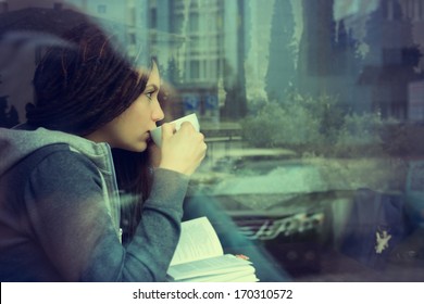 Young woman drinking coffee and reading book sitting indoor in urban cafe. Cafe city lifestyle. Casual portrait of teenager girl. Toned. - Powered by Shutterstock