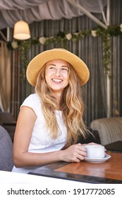 Young Woman Drinking Coffee At Street Cafe. Staycation Tourist. Female Person In Summer Hat. Positive Emotion. Smiling People. Dreaming About Vacation