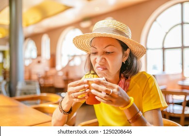 Young woman drinking coffee or tea from paper cup in cafe