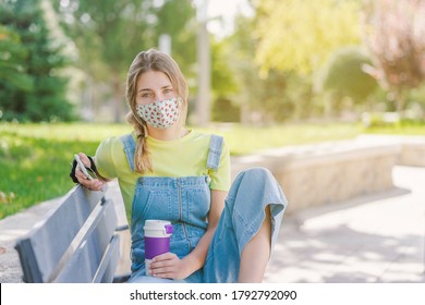 Young Woman Drinking Coffee And Using Her Cell Phone During The Covid Pandemic.