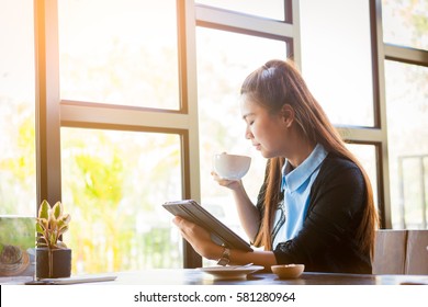 Young woman is drinking coffee with using tablet in coffee shop - Powered by Shutterstock