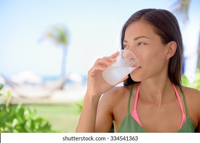 Young Woman Drinking Fresh Water Or Lime Juice At Beach. Female Is Looking Away While Sitting At Outdoor Restaurant. Beautiful Tourist Is Having Healthy Drink During Summer Vacation.