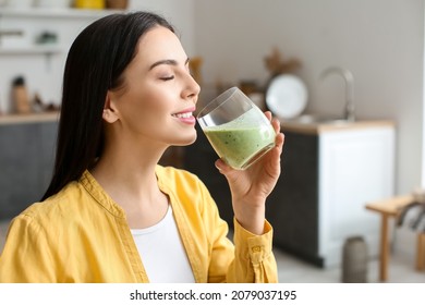 Young Woman Drinking Healthy Green Smoothie In Kitchen