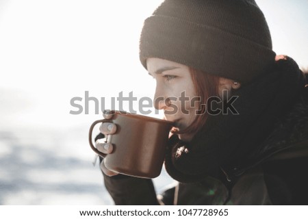 Young woman drinking hot beverage outdoors. Good light in the beginning of spring.