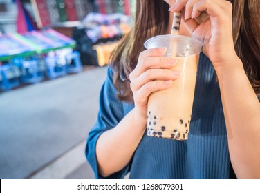 A Young Woman Is Drinking A Plastic Cup Of Bubble Milk Tea With A Straw At A Night Market In Taiwan, Taiwan Delicacy, Close Up.